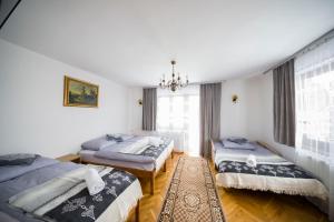 a bedroom with three beds and a chandelier at Apartamenty Harenda 39 in Zakopane