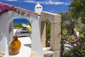 un arco con un jarrón en un patio con flores en Villa Iris - Ela Sardinia in Villa en San Teodoro