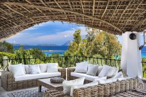 un patio con muebles de mimbre y vistas al océano. en Villa Iris - Ela Sardinia in Villa en San Teodoro