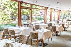 ein Restaurant mit weißen Tischen und Stühlen und Fenstern in der Unterkunft Nerija in Nida