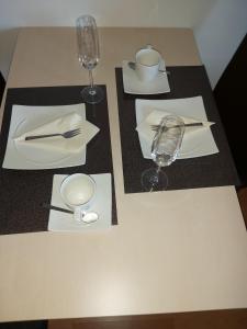 una mesa con dos platos blancos y una copa de vino en Single-Apartment Essen en Essen