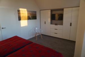 Schlafzimmer mit einem roten Bett und einem TV in der Unterkunft Ferienhaus Marny in Trassenheide