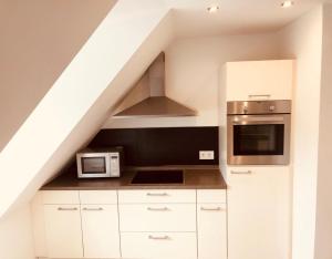 a kitchen with white cabinets and stainless steel appliances at Modern Apartment Wolfsburg City Center Netflix VW 24h in Wolfsburg