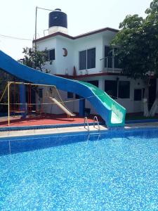 a swimming pool with a slide in front of a house at Hotel Quinta Paraiso in Cocoyoc
