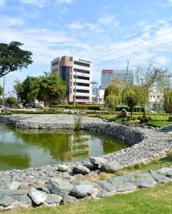 a pond in a park with a building in the background at Hotel Castell - Cerca Del Aeropuerto in Guayaquil