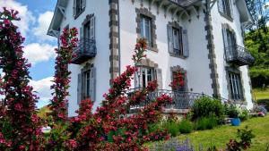 una casa blanca con flores delante en La Maison Normande en Saint-Cirgues-de-Jordanne