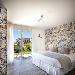 a bedroom with a bed and a sliding glass door at Hôtel Les Agapanthes in Ploubazlanec