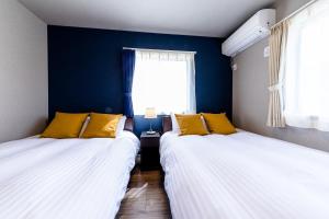 2 camas en una habitación con paredes y ventanas azules en Minamitsuru-gun - House - Vacation STAY 82672, en Fujikawaguchiko