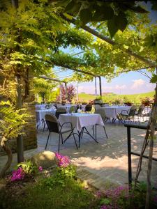 a restaurant with white tables and chairs under a tree at Locanda Rabaya' in Barbaresco