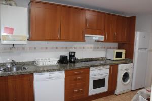 a kitchen with wooden cabinets and a white refrigerator at Apartamento PLAYA ARBEYAL in Gijón