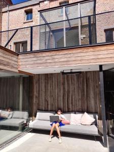 a person laying on a couch with a laptop at Maison Albert in Nieuwpoort