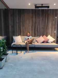 un hombre sentado en un sofá leyendo un libro en Maison Albert, en Nieuwpoort