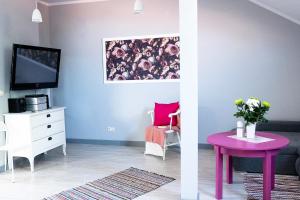 salon z purpurowym stołem i telewizorem w obiekcie Apartament pod Morwą w Lubniewicach