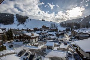 拉克呂薩的住宿－Studio les Granges - Vue montage et village, Centre la Clusaz - AravisTour，雪中的一个小镇,有汽车停泊