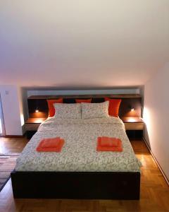 a bedroom with a large bed with two orange pillows at Apartmani Tamara in Vrnjačka Banja