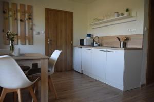 cocina con armarios blancos y mesa de madera en ADEMI Apartments, en Smrečany
