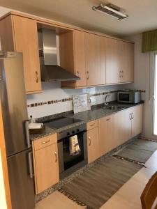 eine Küche mit Holzschränken und einem Kühlschrank aus Edelstahl in der Unterkunft Apartamento Playa San Pedro in Barreiros