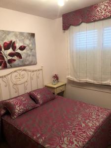 1 dormitorio con 1 cama con colcha roja y ventana en Apartamento Playa San Pedro, en Barreiros