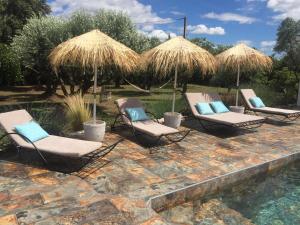 een groep stoelen en parasols naast een zwembad bij mazet provençal in Saint-Gilles