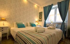 リスボンにあるSweet Suites Guesthouse close to famous Avenue Libertyのベッドルーム1室(青いカーテンと窓付きのベッド2台付)