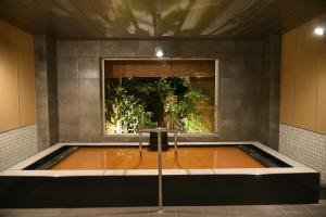 a hot tub in a room with a window at Arima Onsen Taketoritei Maruyama in Kobe