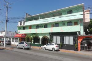 Zwei Autos parkten vor einem grünen Gebäude in der Unterkunft Hotel Costa Maria in Ciudad del Carmen