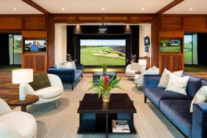 a living room with blue couches and a golf simulator at Four Seasons Resort Hualalai in Kaupulehu