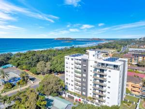 an aerial view of a white building with the ocean in the background at Tradewinds Apartments in Coffs Harbour