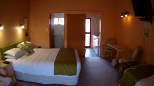 1 dormitorio con cama y escritorio. en Alfa Boutique Motel, en Paihia