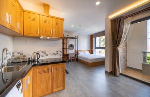 a kitchen with wooden cabinets and a bed in a room at Coast House Boutique Hotel in Nha Trang
