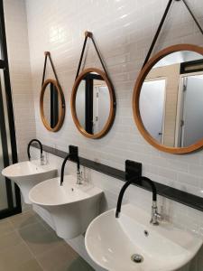 a bathroom with two sinks and two mirrors at The 8 hostel Buriram in Ban Bu Lamduan