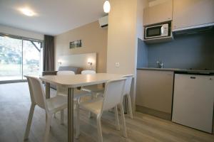 a kitchen and dining room with a table and chairs at Motel des Landes in Bénesse-Maremne