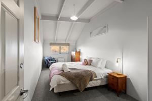 une chambre avec un lit dans une pièce blanche dans l'établissement The Hill Haven Queenstown, à Queenstown
