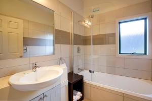 une salle de bain avec un lavabo, une baignoire et un miroir dans l'établissement The Hill Haven Queenstown, à Queenstown 16 autres photos