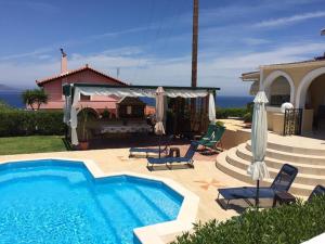 a swimming pool with two chairs and a house at Villa VS in Vathí