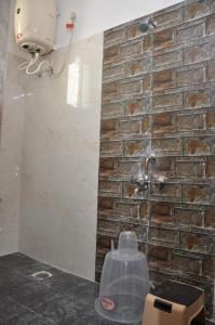 y baño con ducha y pared de piedra. en Nayath Serviced Apartments, en Tirupati