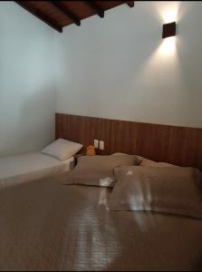 a bedroom with two beds and a light on the wall at Pousada Tia Tuquinha in Piumhi