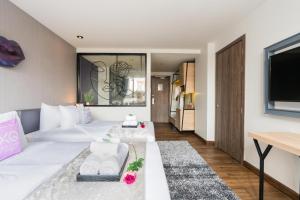 a bedroom with a large white bed and a tv at XQ Pattaya Hotel in Pattaya Central