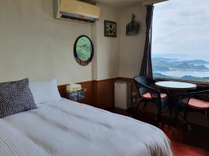 um quarto com uma cama, uma mesa e uma janela em Kao Mama B&B em Jiufen