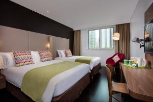 a hotel room with two beds and a desk at Campanile Shanghai Bund Hotel in Shanghai