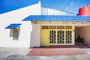 una puerta amarilla de una casa con techo azul en OYO 3252 Lansano Residence Syariah, en Padang