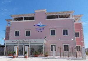 a large pink building with a hotel sign on it at Hotel Belvedere in Margherita di Savoia