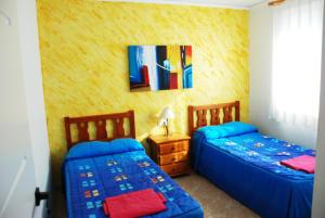 ガンディアにあるGandialco Playa de Gandiaのベッドが2つあり、壁に絵が飾られている寝室