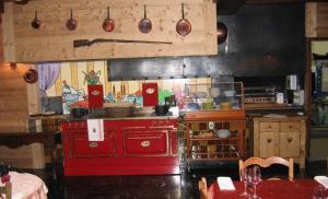 a kitchen with a red stove and some utensils at Hôtel De La Couronne in Mijoux