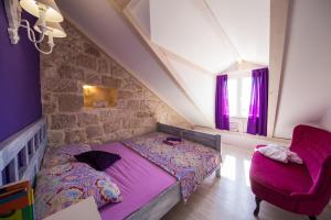 a bedroom with a purple bed and a chair at Guest House Gugily in Dubrovnik