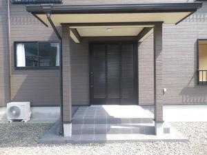 una puerta delantera de una casa con ventilador en Minshuku Iwakawa, en Yakushima