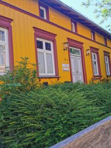 uma casa amarela e vermelha com duas janelas e arbustos em Sommerhaus Seidel - mit kostenlosem Parkplatz - em Stralsund