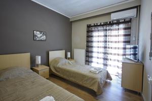 - une chambre avec 2 lits et une fenêtre dans l'établissement C.L.A. City Loux Apartment, à Alexandroúpolis
