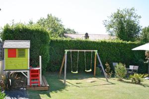 a swing set in a yard with a hedge at Vacances Sur Mer in Saint-Palais-sur-Mer