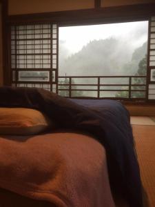 Bett in einem Zimmer mit einem großen Fenster in der Unterkunft Guesthouse Nishiki in Chichibu